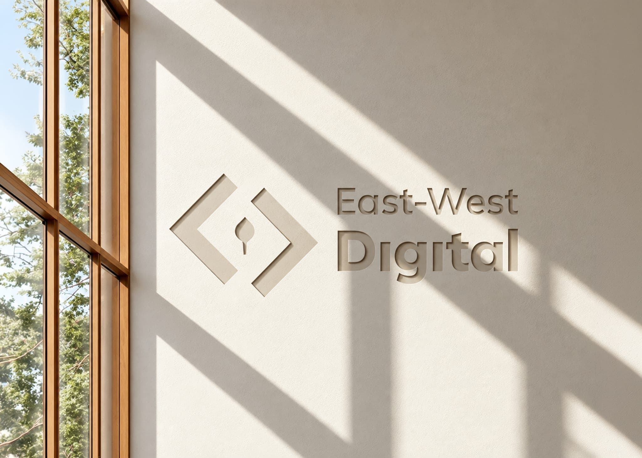 The East-West Digital logo on a sunlit office wall